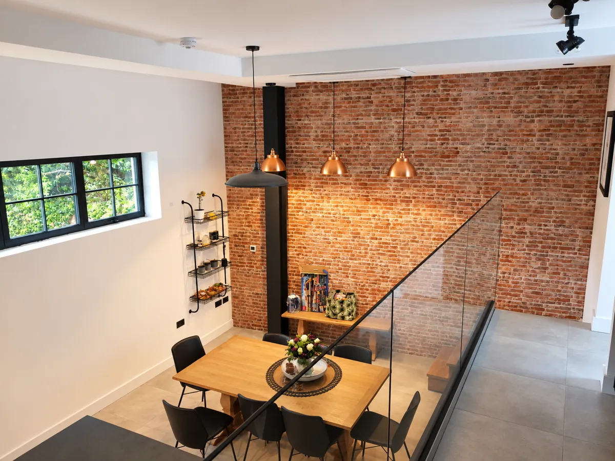 Dining area with exposed brick and a glass balustrade in Wood Green